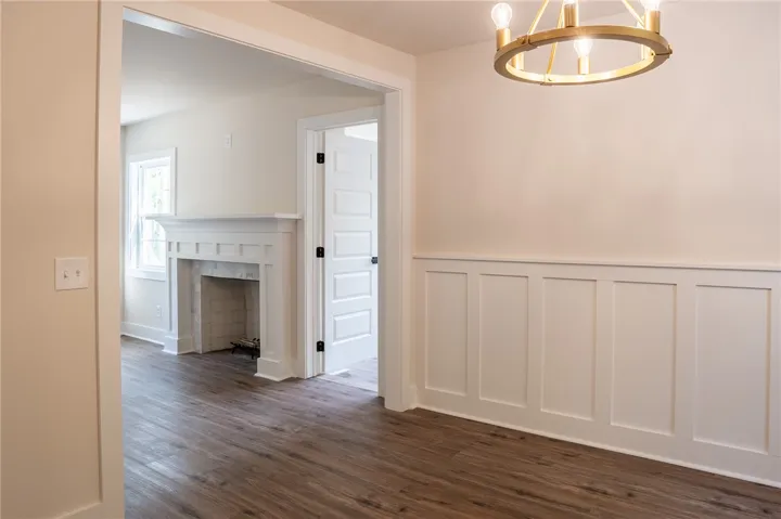 This inviting interior features elegant flooring, a charming fireplace, and wainscoting details.