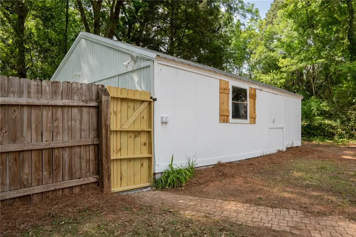 This charming backyard structure features durable wood siding and a practical wooden gate for easy access.