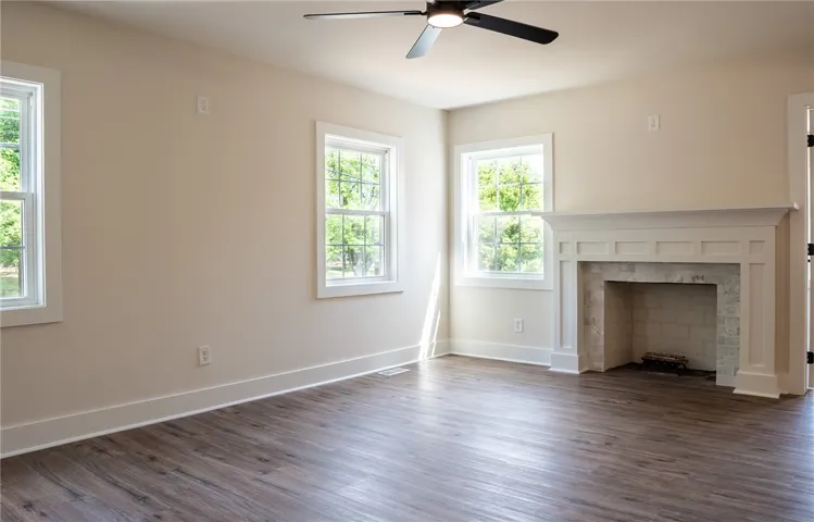 This bright and airy room features ample natural light, a ceiling fan, and a classic fireplace.