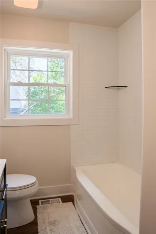 This bright bathroom features a classic bathtub with tiled walls and a large window.