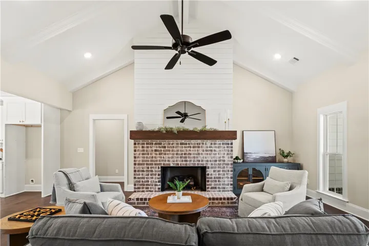 This inviting living area features a grand brick fireplace, high vaulted ceilings, and rich hardwood floors.