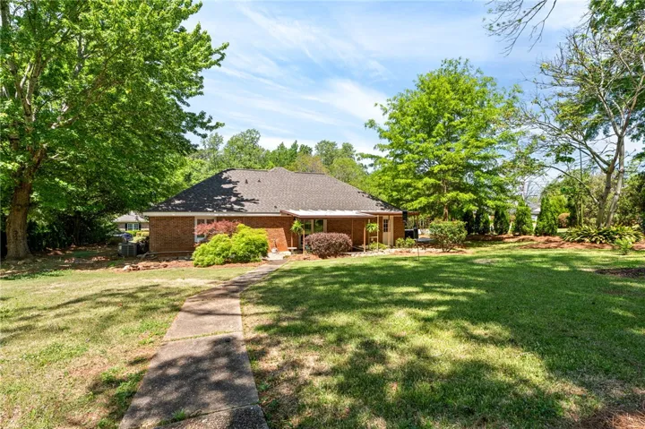 This residence features a timeless brick exterior, nestled amidst mature trees on a sprawling green lawn.