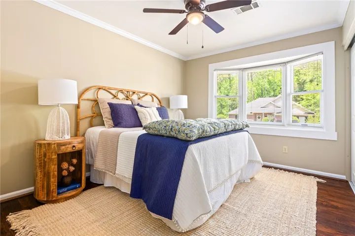 This inviting bedroom features hardwood flooring and a bright bay window