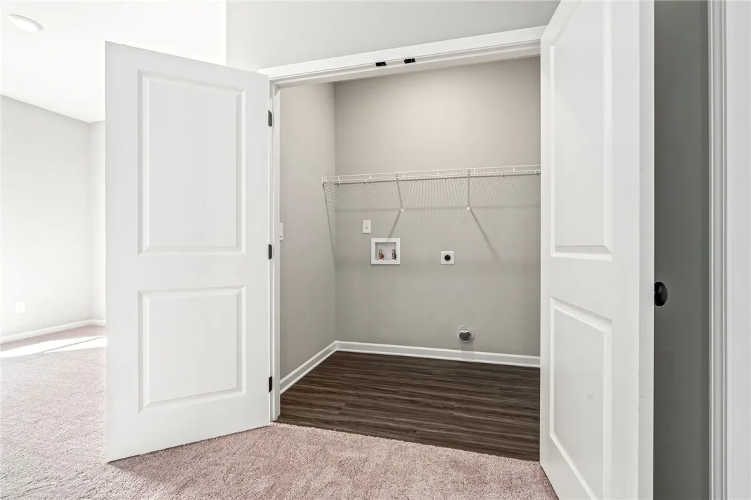 Double doors open to a dedicated laundry closet featuring durable wood-look flooring and built-in wire shelving.