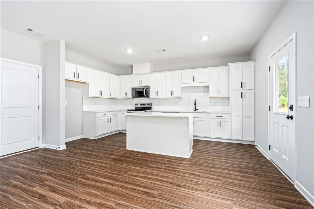 Gleaming wood-look floors ground this modern culinary space outfitted with a central prep island.
