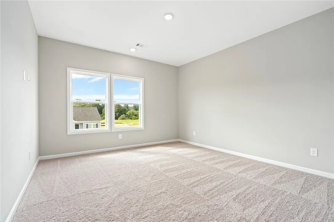 Plush carpeting and wide windows define this versatile, neutral-toned upper-level room.