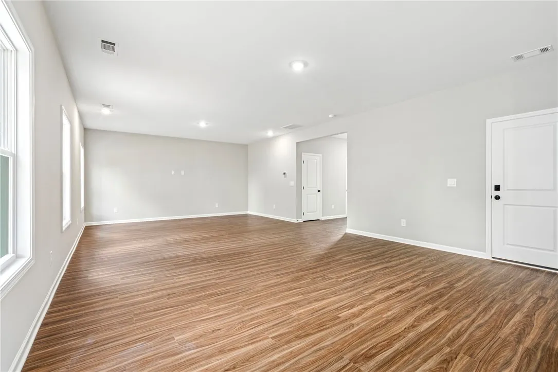 Rich wood-look flooring and recessed lighting define this versatile open living space.