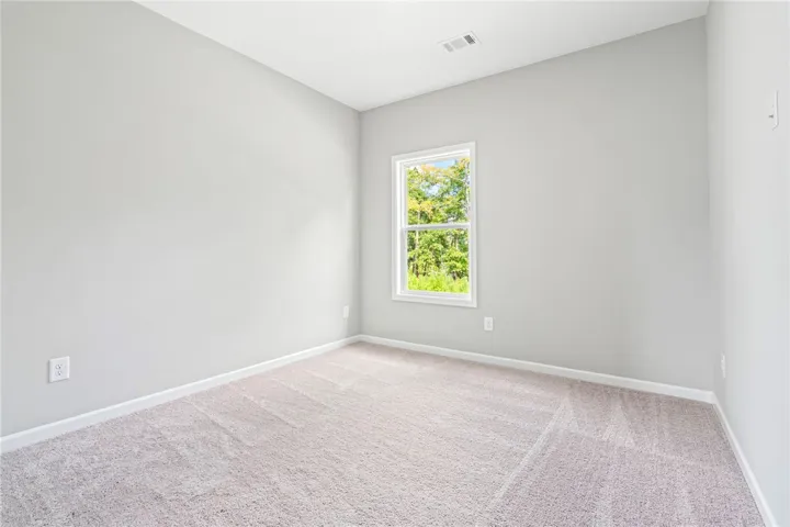 A single window provides natural light and peaceful wooded views to this carpeted room.