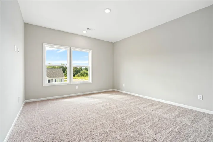 Plush carpeting and wide windows define this versatile, neutral-toned upper-level room.
