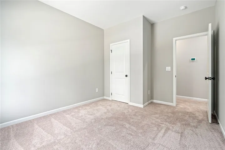 Plush carpeting anchors this versatile room with crisp baseboards and clean white trim.