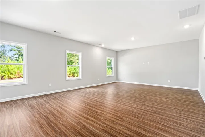 Rich wood floors and recessed lighting anchor this versatile living space filled with natural light.