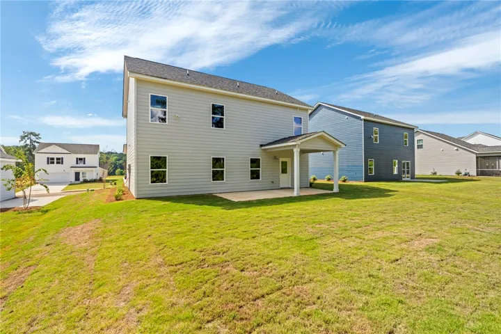 A spacious grassy lawn stretches behind this modern two-story home with a covered patio.