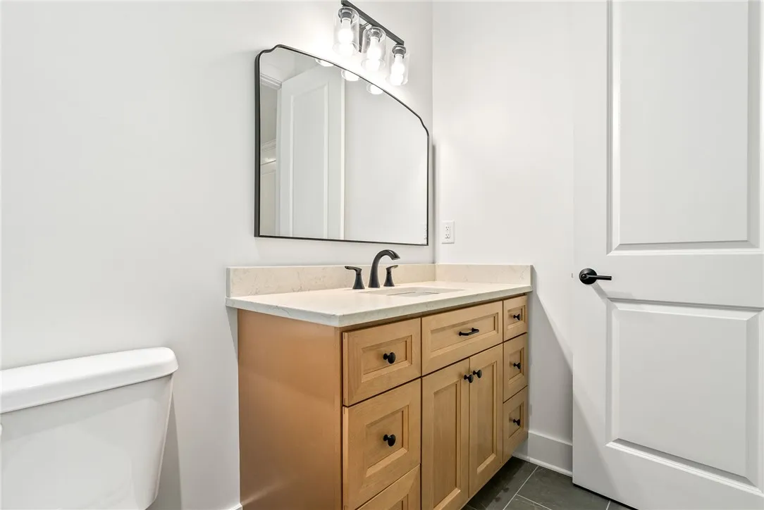 The en suite features tile flooring, a natural wood vanity topped in quartz, and a shower finished with floor-to-ceiling​​‌​​​​‌​​‌‌​‌‌​​​‌‌​‌​‌​‌​​​‌​​ tile.
