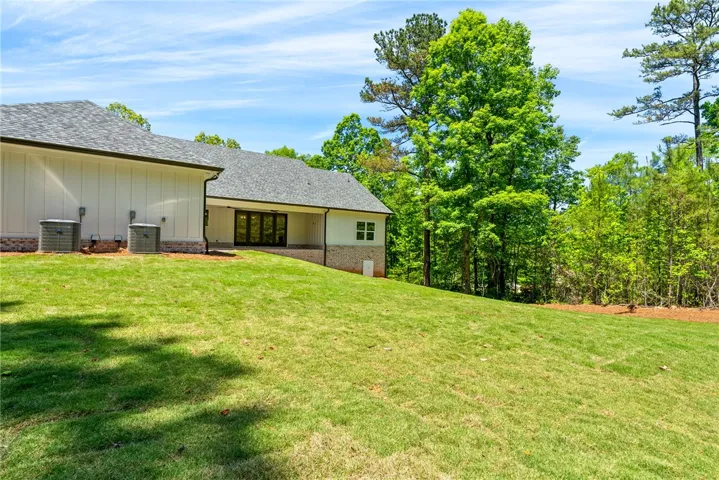 The expansive lawn fully utilizes the acre-size homesite, with trees lining each side to provide privacy and a natural backdrop.