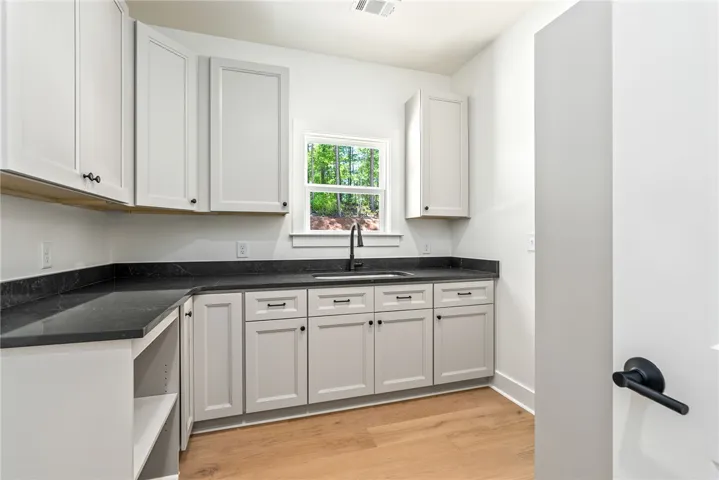 A highly functional laundry room with generous counter space for folding, upper and lower cabinetry, and dedicated shelving for baskets and hanging clothes.