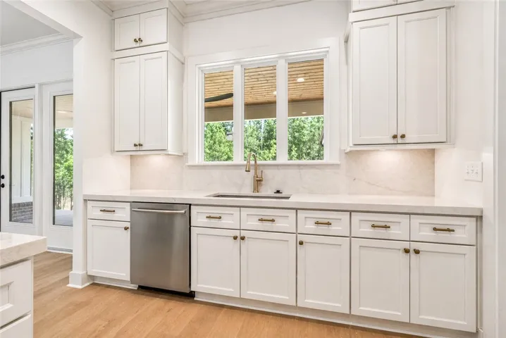 Ceiling-height cabinetry is topped with beautiful quartz, and the sink overlooks the rear porch and backyard beyond.