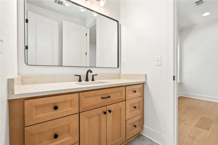 The Jack-and-Jill bath provides Bedrooms 2 and 3 with private vanities, while hexagonal tile and black-framed mirrors add a chic touch.