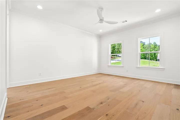 The primary bedroom is accessed via a private hallway and features hardwood floors, multiple windows, and convenient access to the home’s utility spaces.