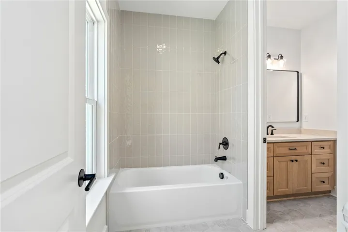 A true Jack-and-Jill design, bath 2 offers private vanity spaces for each bedroom and a shared wet area with full-height tile in a refined pattern.