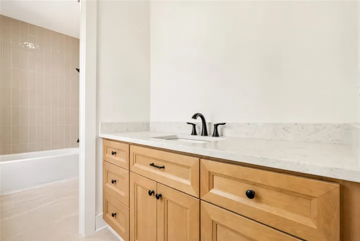 A true Jack-and-Jill design, Bath 2 offers private vanity spaces for each bedroom and a shared wet area with full-height tile in a refined pattern.
