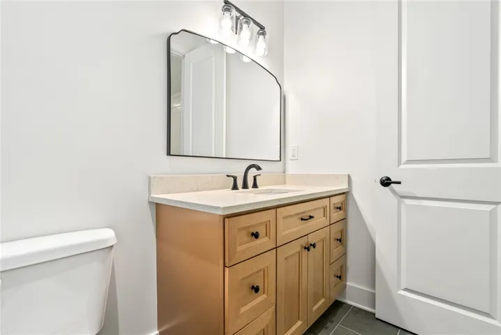 The en suite features tile flooring, a natural wood vanity topped in quartz, and a shower finished with floor-to-ceiling​​‌​​​​‌​​‌‌​‌‌​​​‌‌​‌​‌​‌​​​‌​​ tile.