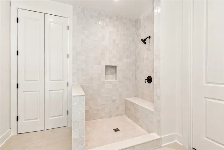 The primary shower showcases chic, full-height tile, a wall-to-wall bench, and a thoughtfully integrated niche.