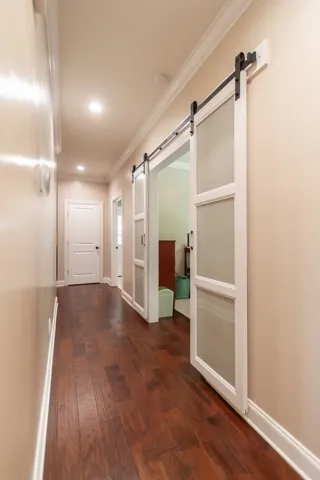 Elegant hallway features rich hardwood flooring and sleek barn doors, adding character and warmth to the home.