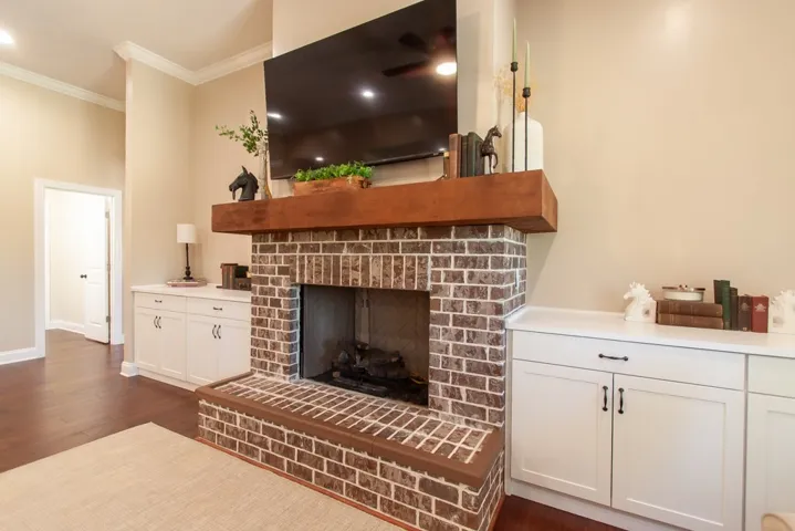 Living area features a classic brick fireplace with a sturdy wooden mantel and built-ins.