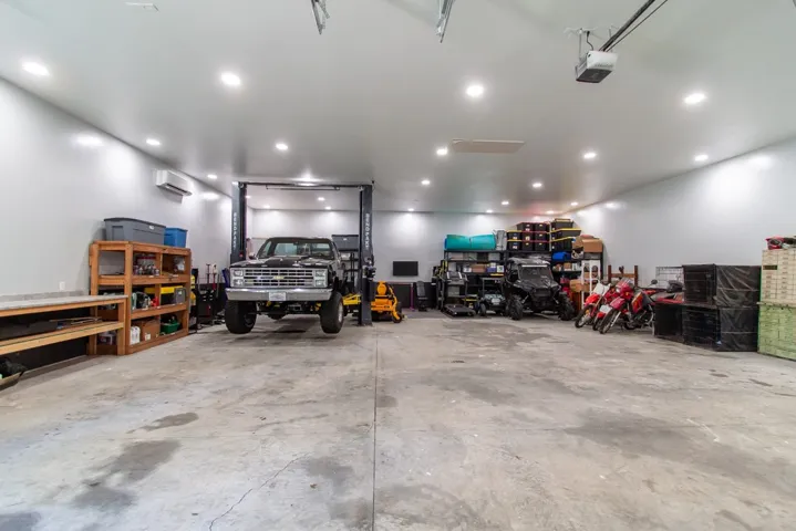 Heated and cooled workshop with ample room for vehicles and equipment, featuring overhead lighting.