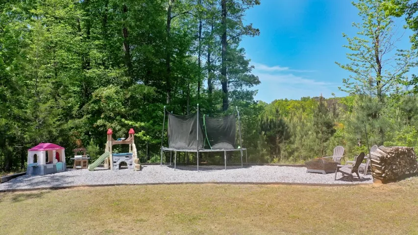 This spacious yard offers a vibrant play area and a serene fire pit, perfect for outdoor enjoyment.
