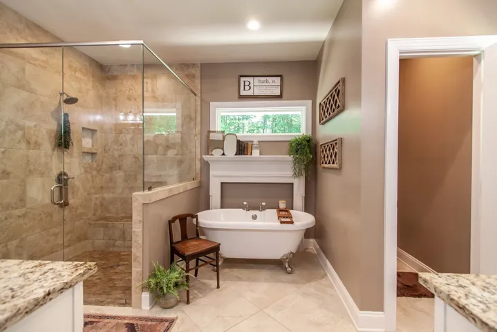 This serene bathroom offers a luxurious walk-in shower and a classic freestanding tub.