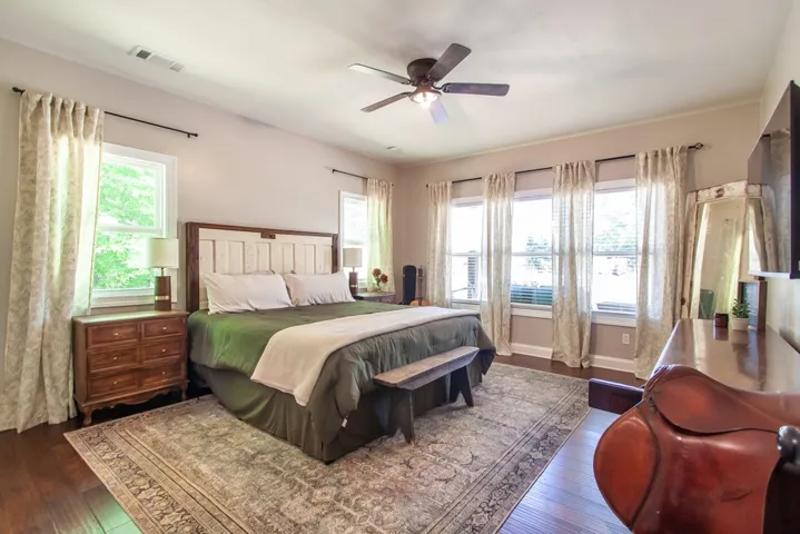 Spacious primary bedroom offers ample natural light and comfortable wood flooring, creating a relaxing retreat.