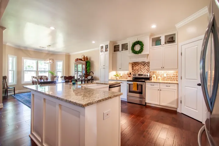 This spacious kitchen offers ample granite counter space, stainless steel appliances, and rich wood flooring.