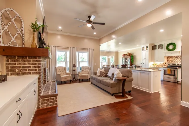 An inviting open-concept living space features warm wood flooring and a classic brick fireplace.