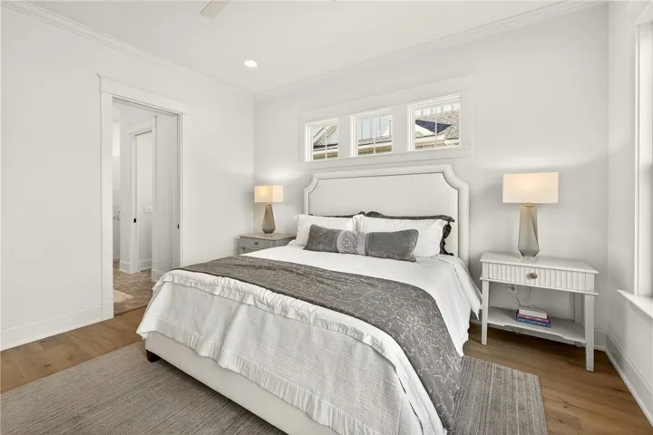 This bright and inviting bedroom features warm wood flooring and elegant crown molding.