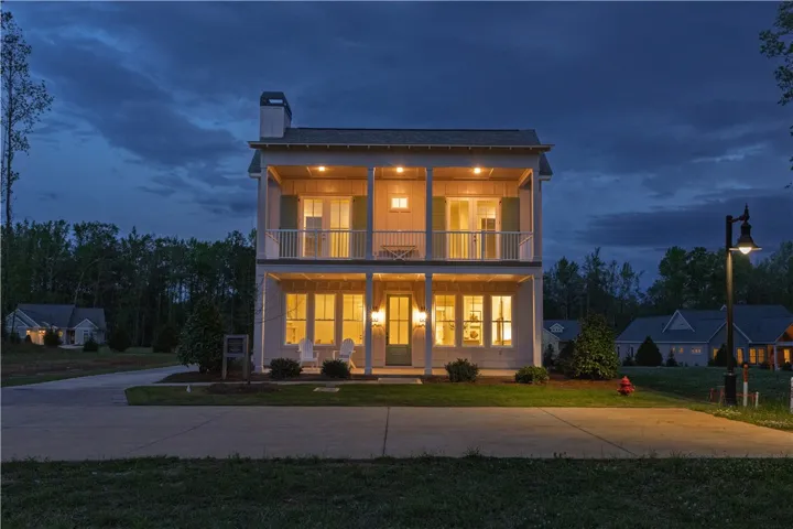 This two-story home, illuminated at dusk, showcases inviting, classic architectural elements.