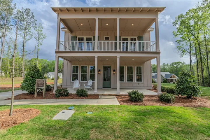 This two-story Aspen Eagle Model presents a charming exterior with a welcoming porch and upper-level balcony.