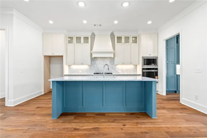 Thoughtfully designed, the kitchen offers a large marble-topped island, custom solid and glass-front cabinetry, ceiling-height custom cabinetry, a gas range, and a double sink.