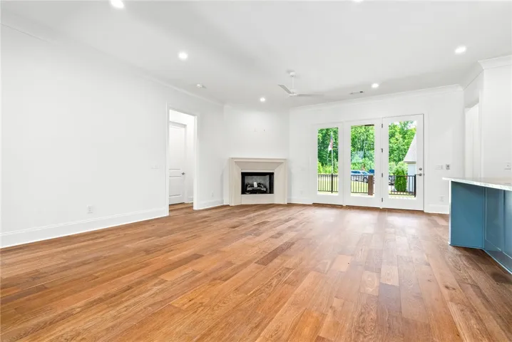The great room features beautiful wood floors, a triple-door opening to the porch, and a gas fireplace with a cast-stone surround—all contributing to an open, inviting space designed for gathering.