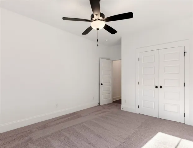 This spacious room features neutral carpet, a ceiling fan, and ample closet space.