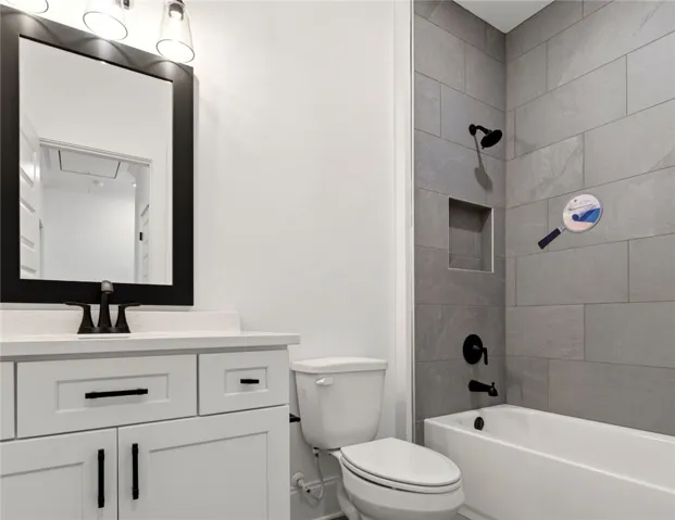 This sleek bathroom features a contemporary vanity, large mirror, and tiled shower with a built-in niche.