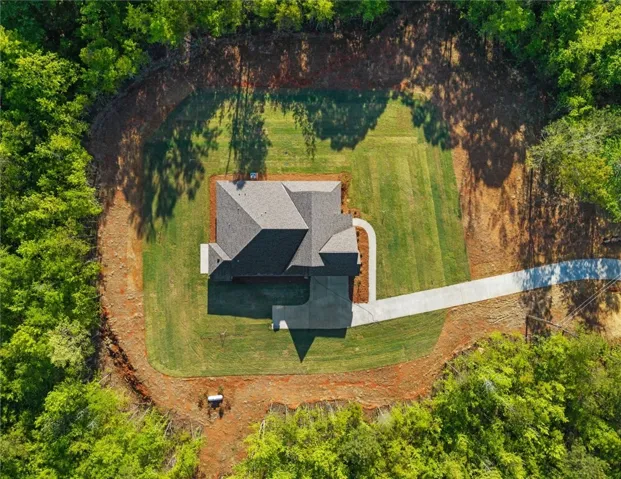 This aerial view showcases a meticulously maintained home with lush green surroundings and a spacious driveway.