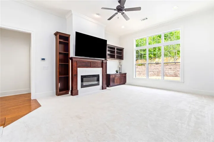 Bright and airy living area featuring a fireplace and large windows overlooking lush greenery.