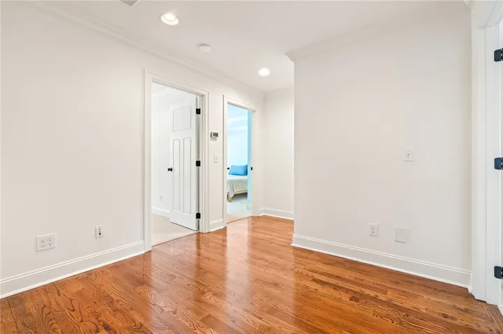 Bright hallway with polished hardwood floors and modern recessed lighting.