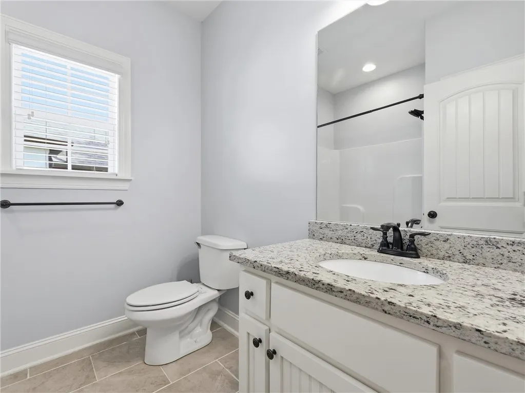 This bright bathroom features a spacious vanity with elegant granite countertops and a window for natural light.