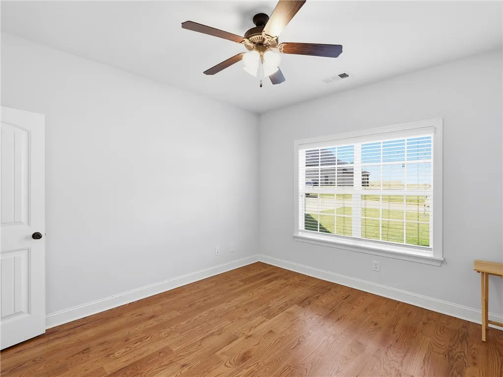 This bright room features beautiful hardwood flooring and a ceiling fan, offering comfortable living.