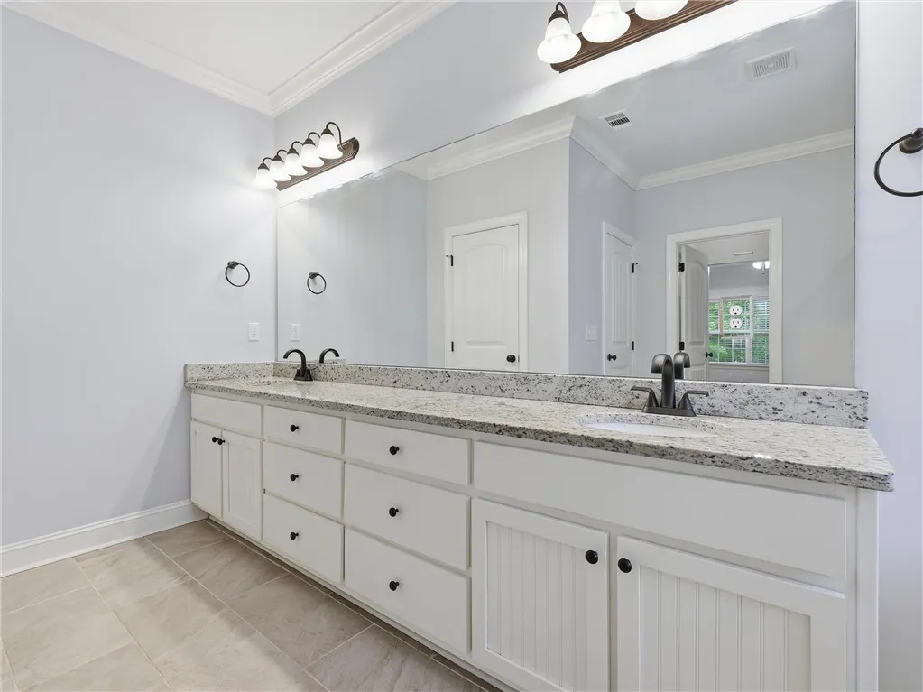 This spacious bathroom offers a large double vanity with ample storage and modern finishes.