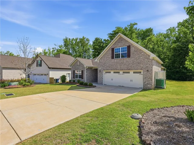 This charming home offers a spacious driveway and an inviting exterior, set against a backdrop of lush greenery.