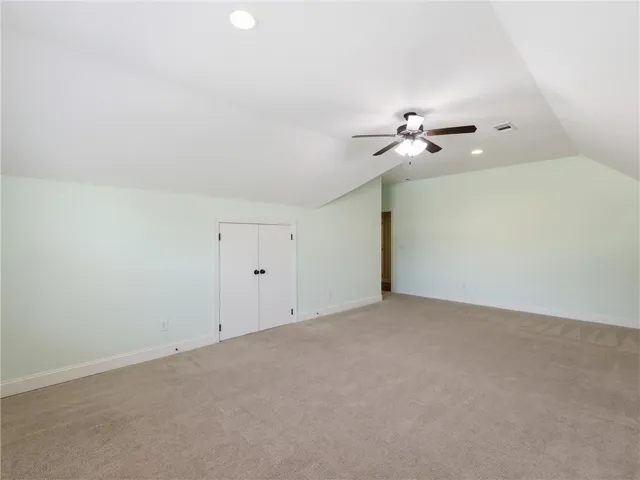 This spacious bonus room features soft carpeted flooring and vaulted ceilings, ready for customization.