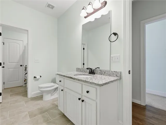 This bathroom features elegant granite counters, sleek tile flooring, and a well-appointed vanity with ample storage.